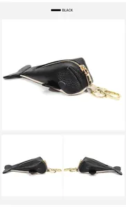 Detail view of a black leather whale-shaped key pouch with premium gold zipper and hardware