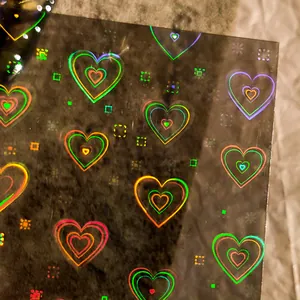 Minimalist holographic laser nail stickers featuring rainbow heart patterns on black film