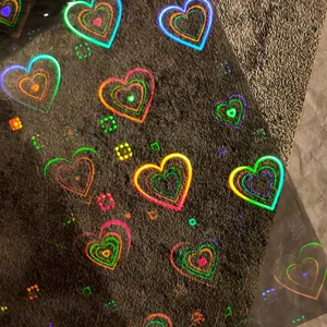 Holographic heart nail art stickers with colorful neon outlines on a dark background
