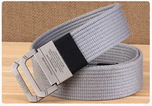 Detail van zilvergrijze canvas riem met matte D-ring gesp en geweven textuur op hout