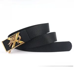 Détail de la ceinture noire en nylon épais avec boucle dorée au design de crocodile