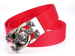 Detail of red nylon tactical belt featuring an embossed silver wolf head buckle