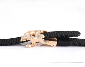 Detail of rose gold buckle with white rhinestones on black woven nylon belt