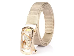 Detail of beige nylon woven belt featuring a gold automatic buckle with a crystal swan
