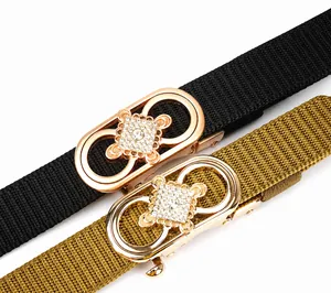 Détail de boucles dorées avec strass sur des ceintures tressées noires et kaki