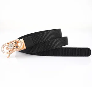 Détail de ceinture noire en nylon avec boucle dorée à double anneau et strass fleuris