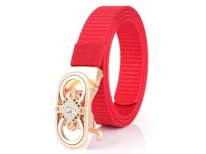 Detail of red nylon belt with rose gold buckle featuring rhinestones and weave texture