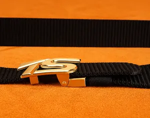Detail of adjustable black nylon belt with golden S-shaped automatic metal buckle