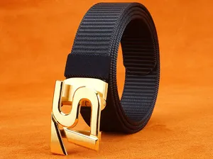 Detail of black nylon belt with automatic gold metal buckle featuring a textured S design
