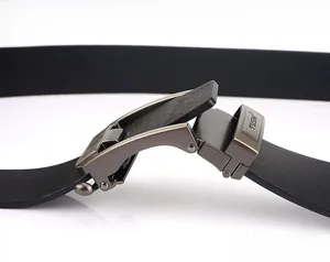 Macro detail of men's matte gunmetal automatic belt buckle with engraved TUSHI logo