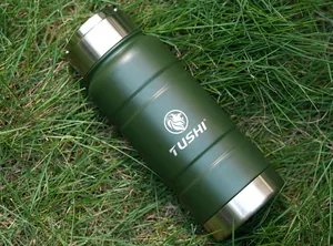 Macro detail of military green stainless steel tactical bottle with TUSHI logo on grass