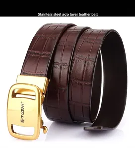Macro shot of dark brown genuine leather belt with crocodile pattern and golden buckle