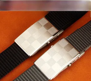 Macro shot of nylon canvas belts with brushed metal buckles on orange textured background