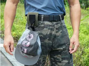 Tactical nylon hook for Molle system on a belt showing usage for hanging a cap outdoors