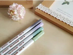 Detailed view of STA metallic fine tip paint pens set on a decorative wooden background