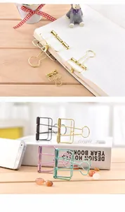 Detailed view of colorful hollow metal binder clips in multiple sizes on a wooden desk
