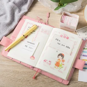 Pink washi tape set with leather journal and yellow fountain pen on a wooden desk