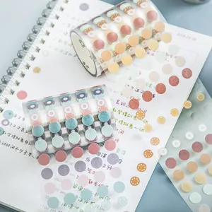 Pastel washi tape rolls with colorful dot stickers on a notebook for journaling