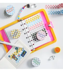 Flachbild von buntem Schachbrett-Washi-Tape-Set mit gelbem Planer und Aufklebern