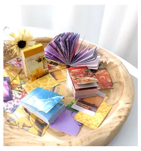 Gros plan de cartes d'art floral vintage et de carnets colorés sur un plateau en bois