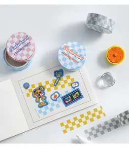 Makroaufnahme von buntem Schachbrett-Washi-Tape und Dekostickern auf einem Notizbuch