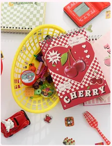 Makro-Detail des roten Kirsch-Spiralnotizbuchs mit Retro-Herz-Cover und bunten Requisiten