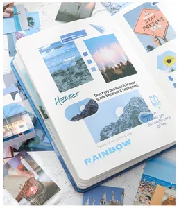 Detail of open scrapbooking notebook with aesthetic landscape stickers and quotes