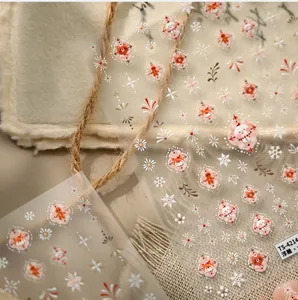 Detail of embossed Christmas nail stickers with snowman and fox designs on a warm rug
