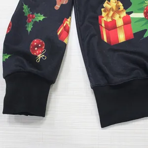 Black Christmas sweatshirt with festive prints and ribbed cuffs on plaid background