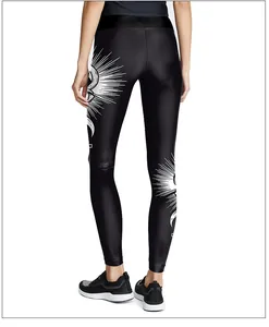 Detail of high-stretch black yoga leggings with white sunburst and eye print on the calf