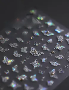 Detailed macro view of holographic butterfly nail stickers with 3D embossed floral patterns