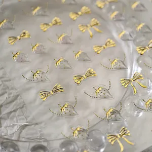 Detail of golden embossed bow and strawberry nail art stickers with 3D foil texture
