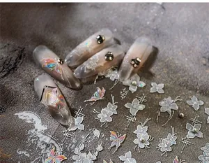 Detailed view of jelly gradient nail tips with 3D white flowers and holographic butterfly decals
