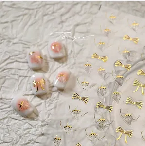 Detail of 3D gold embossed bow and strawberry nail art stickers on white manicure