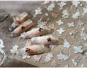 Macro view of floral and butterfly nail art decals applied on matte clear false nails