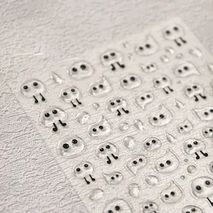 Detailed macro view of 3D transparent ghost nail art stickers with cute gold stamping