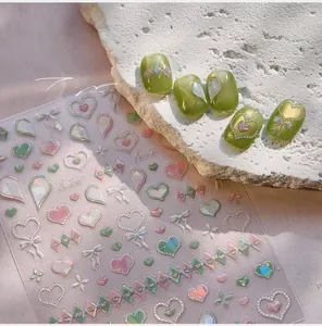 Detail of laser heart nail stickers with bow patterns applied on green manicured nails