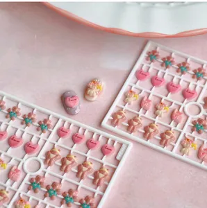 Detailed close-up of cute 3D resin bear and heart nail art charms set in pink tones