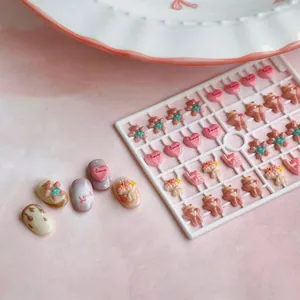 Cute resin nail art charms featuring love hearts and bears on a pink display rack