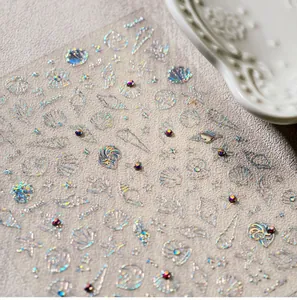 Primer plano de pegatinas de uñas de conchas y estrellas de mar con pedrería 3D y láser