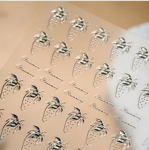 Detailed close-up of metallic strawberry nail stickers with embossed silver texture