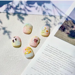 Detailed view of handmade press-on nails featuring cute cow and bee relief patterns