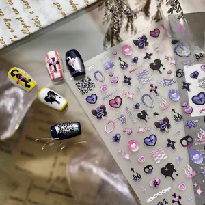 Close-up of Y2K nail art stickers with purple hearts, black crosses and flame patterns