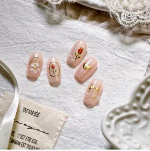 Vue détaillée de faux ongles floraux avec tulipes dorées et petites perles