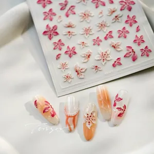 Macro shot of 3D embossed pink and white floral nail art stickers with sample tips