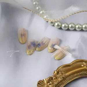 Détail des stickers ongles fleurs gaufrés or avec nœud 3D sur un fond en marbre