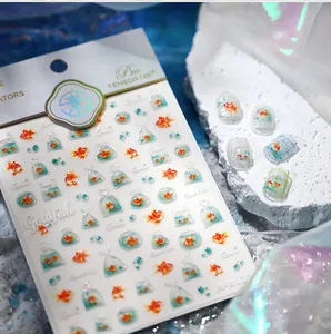 Macro shot of 3D goldfish nail stickers with water bag designs on a display nail