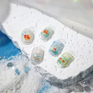 Macro shot of 3D goldfish nail art stickers with shell shimmer and blue grid lines