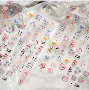 Detail of cute panda and cat nail stickers with hearts and rainbows on a white ceramic plate