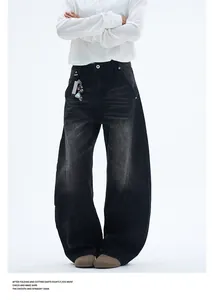 Detail of washed black baggy jeans featuring curved panel stitching and metal key chain